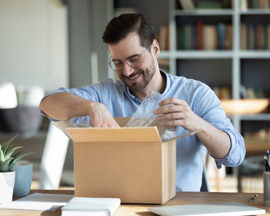 Smiling man with glasses opening box